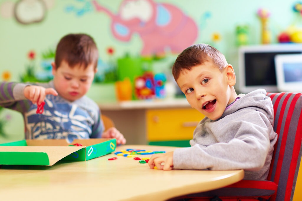 cute kids with special needs playing with developing toys while sitting at the desk in daycare center